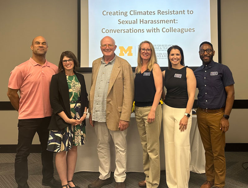 Six people standing in front of the room with a Creating Climates Resistant to Sexual Harassment: Conversations with Colleagues PowerPoint behind them.