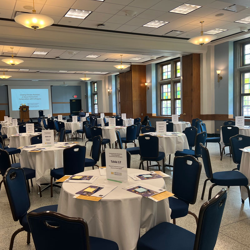 A group of table and chairs set up for a speaker with presentations materials at each table.