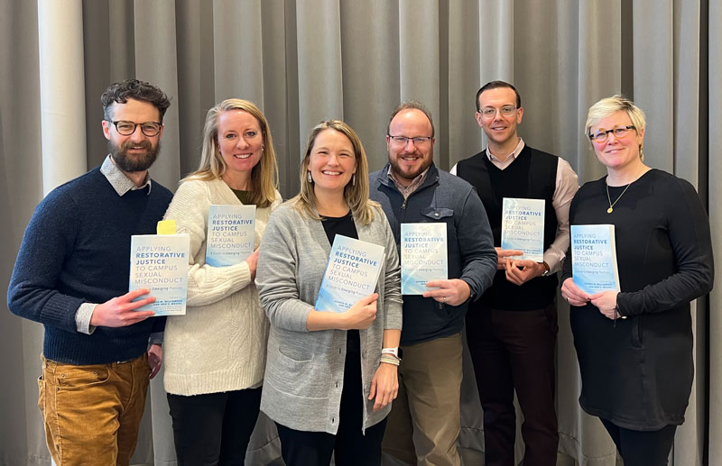 A group of people each holding up the Applying Restorative Justice to Campus Sexual Misconduct book.