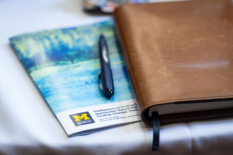 PEAR conference pamphlet next to a leather-bound notebook.