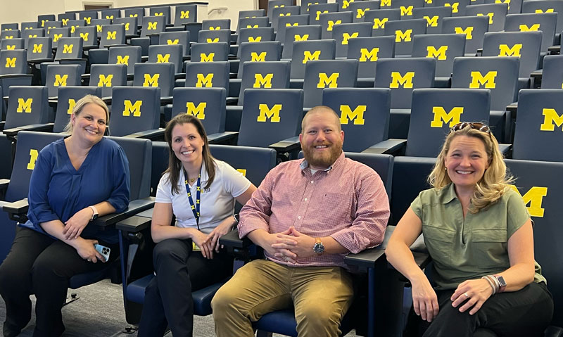 Four people sitting in block M stadium seating.