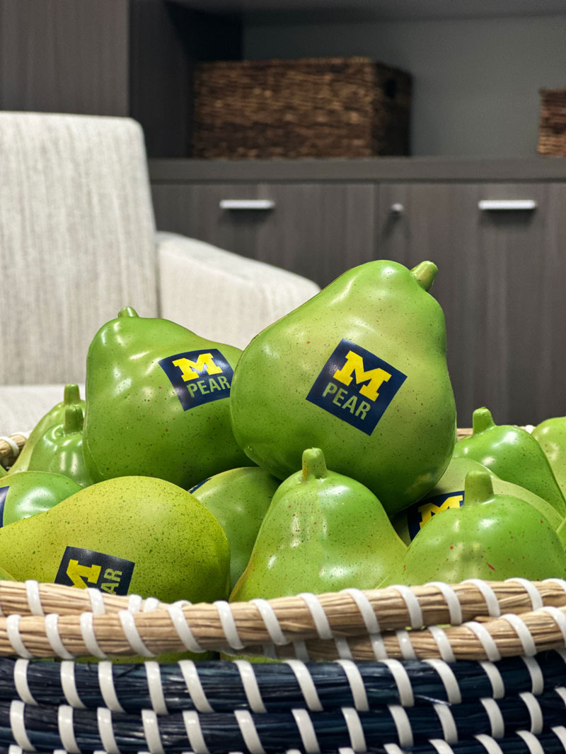 Pear shaped stress balls with the Block M PEAR logo sitting in a basket in a conference room.