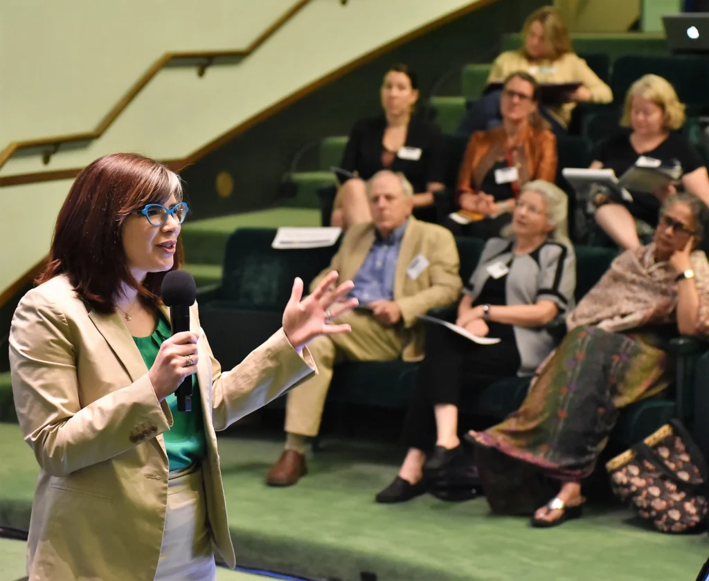 Conference speaker inside the Rackham Auditorium giving a presentation.