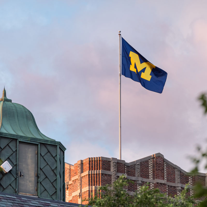 Block M flag flying over a campus building.